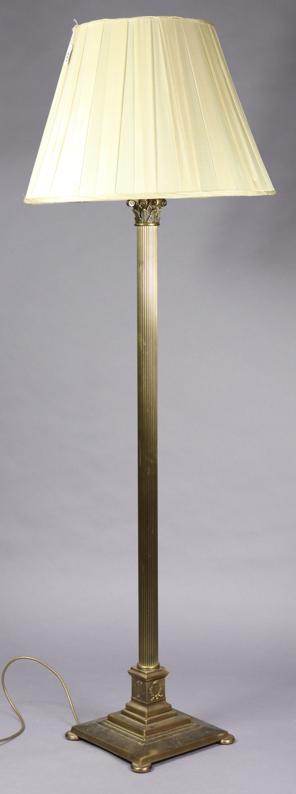 A brass Corinthian-style standard lamp, on a square stepped base, with shade, 66” high.