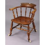 A spindle-back captain’s chair with a hard seat, & on turned legs with ceramic castors, & with