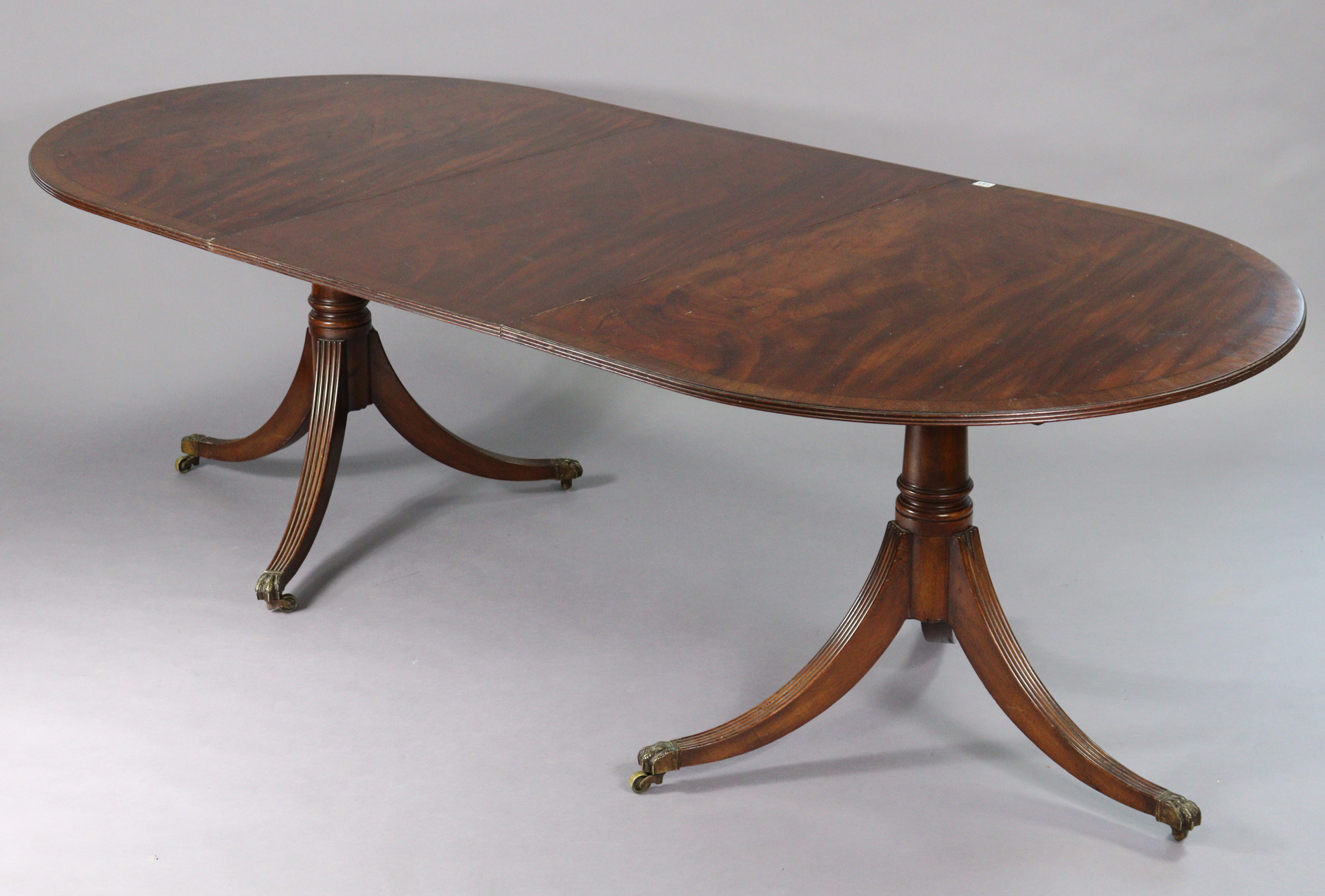 A regency-style inlaid-mahogany twin-pedestal tilt top extending dining table with d-shaped ends,