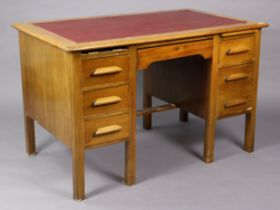 A mid-20th century light oak kneehole office desk inset crimson leatherette, fitted with an