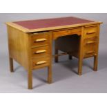 A mid-20th century light oak kneehole office desk inset crimson leatherette, fitted with an