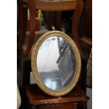 A gilt frame oval dressing table mirror with a beaded edge & on an easel support, 18¼” high;