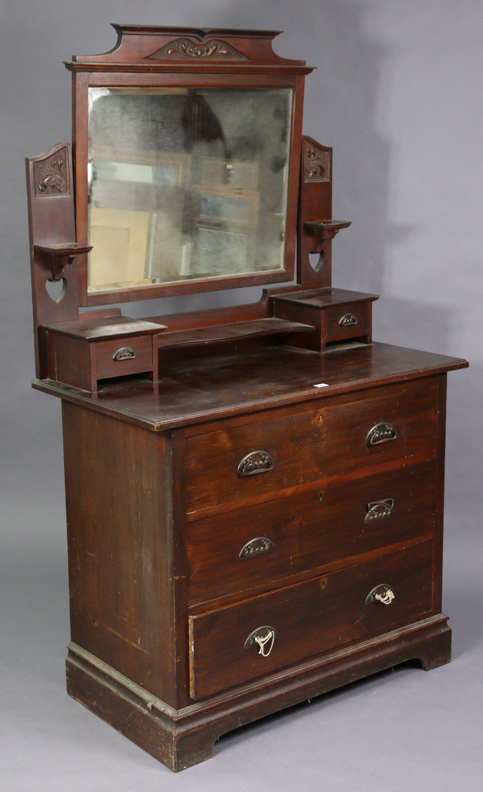 An Edwardian walnut dressing chest with a rectangular swing mirror to the stage back, fitted three