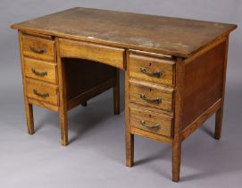 A mid-20th century oak knee-hole office desk fitted with two brushing slides above an arrangement of