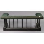 An ebonised wooden and wrought-iron club fender with a padded seat upholstered green material, 61”