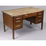 A mid-20th century oak knee-hole office desk fitted with an arrangement of seven drawers and two
