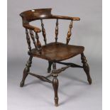 A spindle-back captain’s chair with a hard seat, and on turned legs with spindle stretchers.
