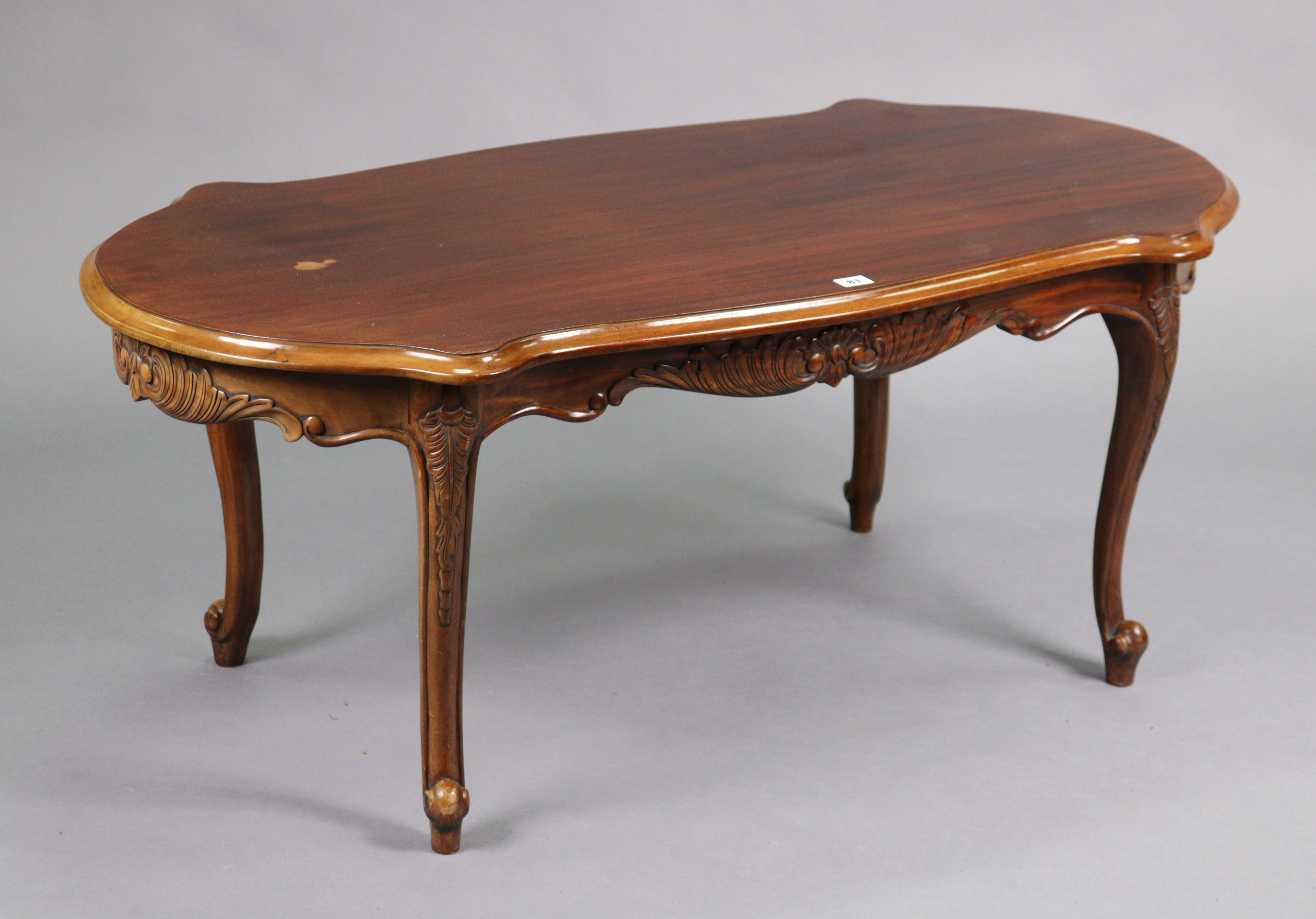 A reproduction mahogany low coffee table with a moulded edge to the shaped top & on four slender