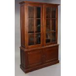 A hardwood tall bookcase fitted two shelves enclosed by a pair of glazed doors above cupboard
