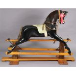 A HADDON ROCKERS OF DIDCOT LARGE BLACK-FINISH ROCKING HORSE ON PINE TRESTLE BASE, 64” long x 50”