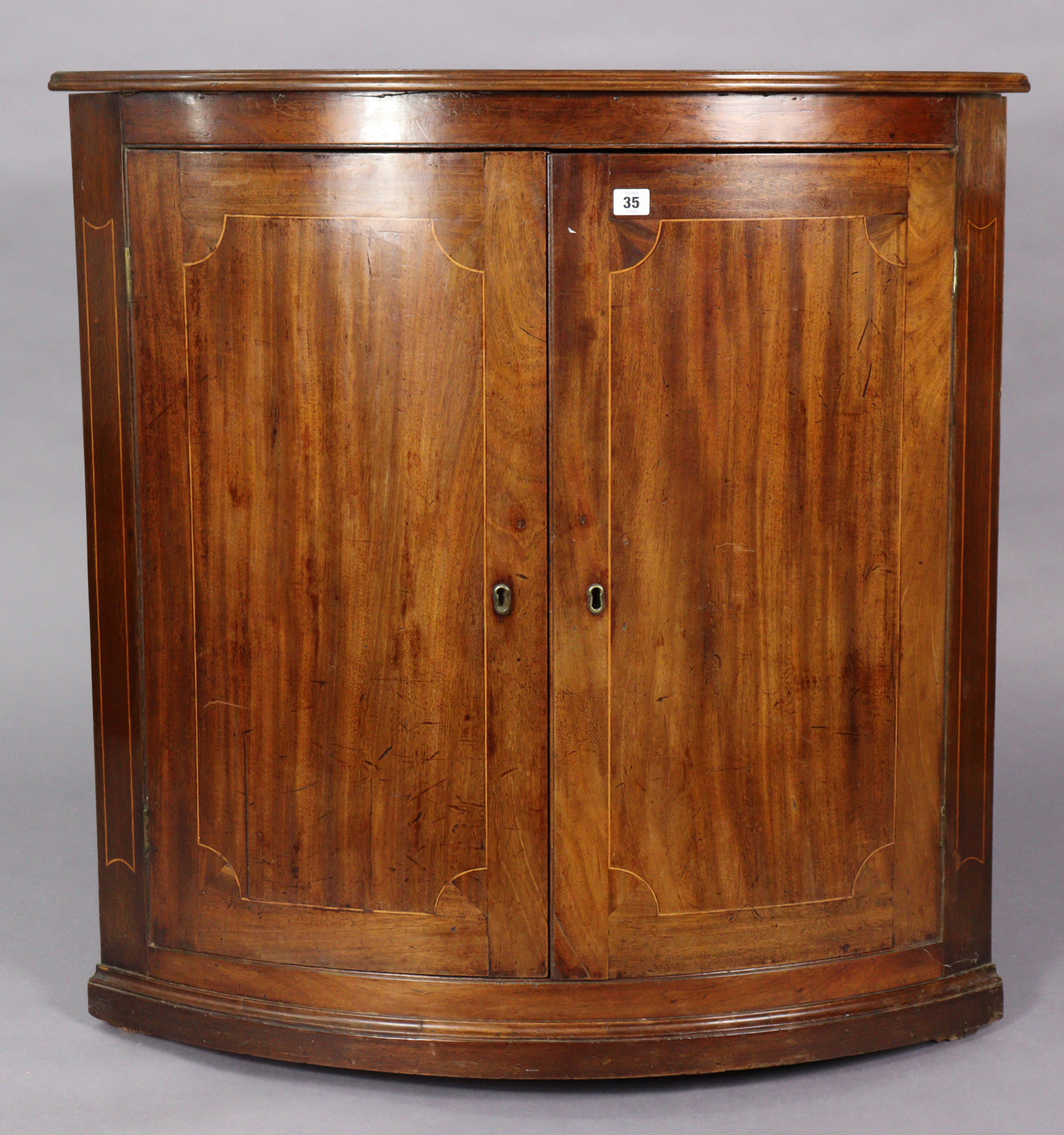 A 19th century inlaid-mahogany large bow-front hanging corner cupboard, fitted two shelves, 36” wide