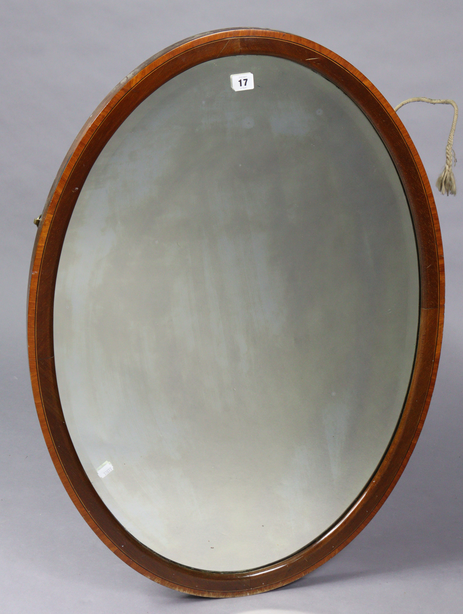 An Edwardian inlaid-mahogany frame oval wall mirror inset with a bevelled plate, 25¾” wide x 35¾”
