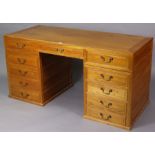 A Chinese-style teak pedestal desk fitted with an arrangement of eleven drawers with brass swing