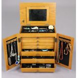 A pine-finish jewellery cabinet, 15” wide x 16” high, containing various items of costume jewellery.
