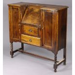 A 1930’s oak bureau with a fitted interior enclosed by a hinged fall-front above two long drawers,