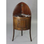 A mahogany bow-front small standing corner cabinet enclosed by a panel door above a drawer, & on