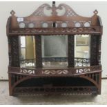 An Edwardian fret carved mahogany hanging shelf with a mirrored back and three open tiers  24"h