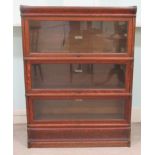 An early 20thC oak, three section Globe Wernicke bookcase with rising glazed doors, on a plinth