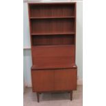 A 1960s/70s teak living room unit with an arrangement of open shelves, doors and a fall flap, raised