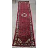 A Persian runner, decorated with a central pole medallion, on a red ground  125" x 30"