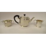 A three piece silver tea set of cylindrical form with vertically line engraved ornament