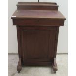 A late Victorian mahogany Davenport with a hinged red hide scriber, over a panelled door, on a