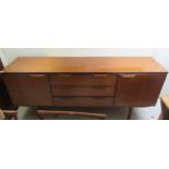 A 1960s/70s teak sideboard with three central drawers, flanked by two cupboard doors, raised on