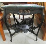 An Edwardian ebonised centre table, having a foliate carved top, raised on slender cabriole legs,