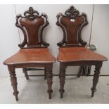 A pair of early Victorian mahogany framed hall chairs with solid backs and seats, raised on