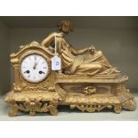 A late 19thC gilded spelter mantle clock, surmounted by a reclining female figure; the 8 day