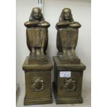A pair of 20thC cast brass fire dogs, fashioned as Pharaoh's, on plinths  14"h overall  6"deep