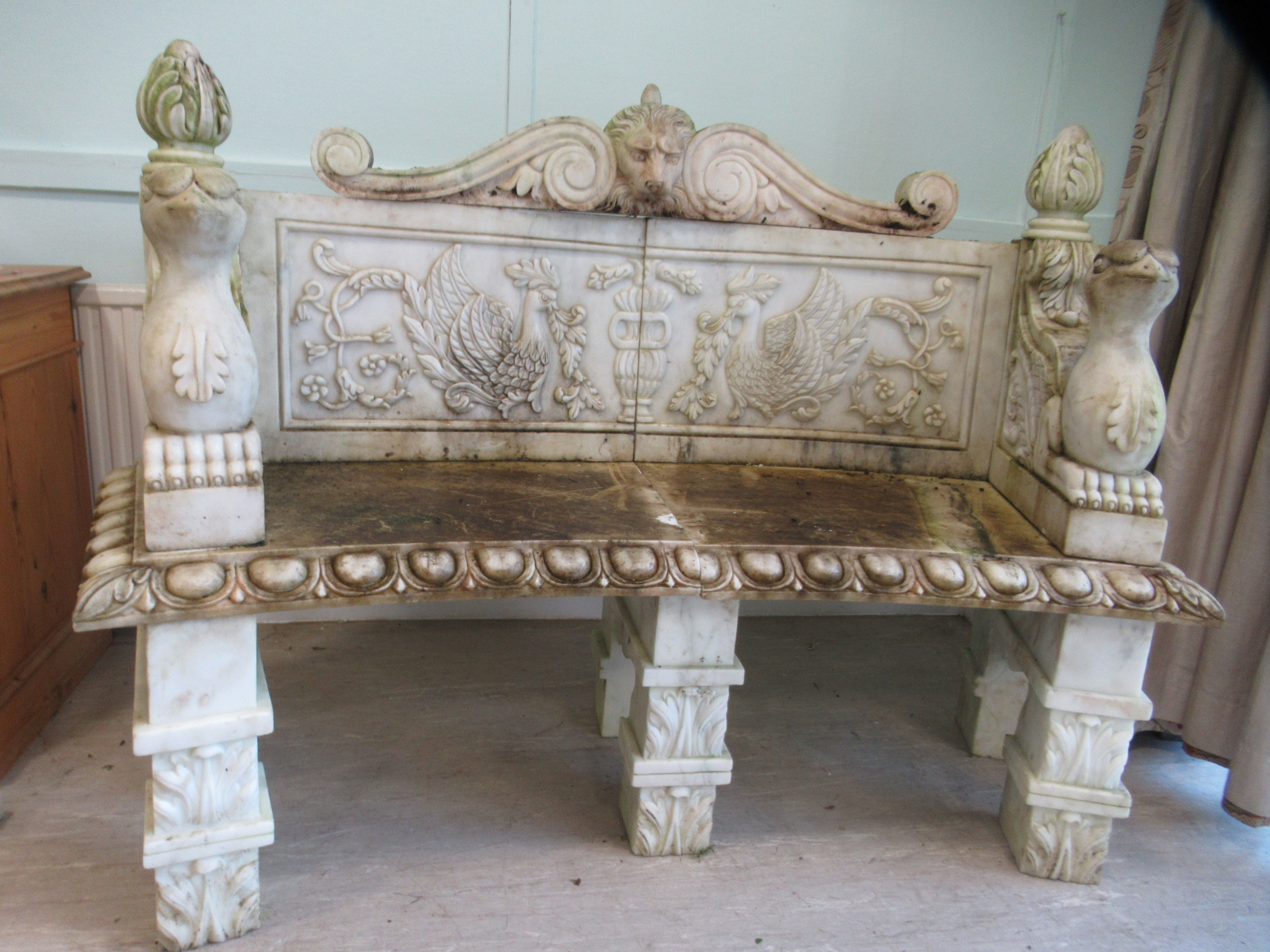A carved marble terrace seat of in-curved design, featuring mythical birds, a lions' head and