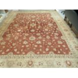 A carpet, decorated in tones of iron red and beige with a multi-guard border and central floral