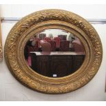 A modern mirror, the oval bevelled plate set in an ornate gilded gesso frame  30" x 21"