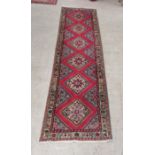 A Persian runner, decorated with repeating red diamond formations and floral designs, on a multi-