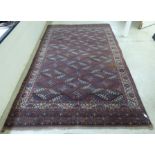 A Turkoman rug, decorated with repeating crossover designs, on a red ground  74" x 127"