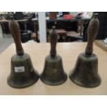 A graduated set of three cast metal hand bells, on turned wooden handles  9"-11.5"h