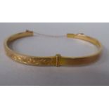 A 9ct gold bangle with engraved decoration