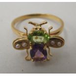 A (probably silver gilt) ring, surmounted by a bee, set with pearls, a peridot and amethyst stones