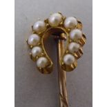 A yellow metal stick pin, featuring a seed pearl set horseshoe