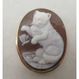 A gold coloured metal framed cameo brooch, depicting a kitten playing with a butterfly  stamped 750