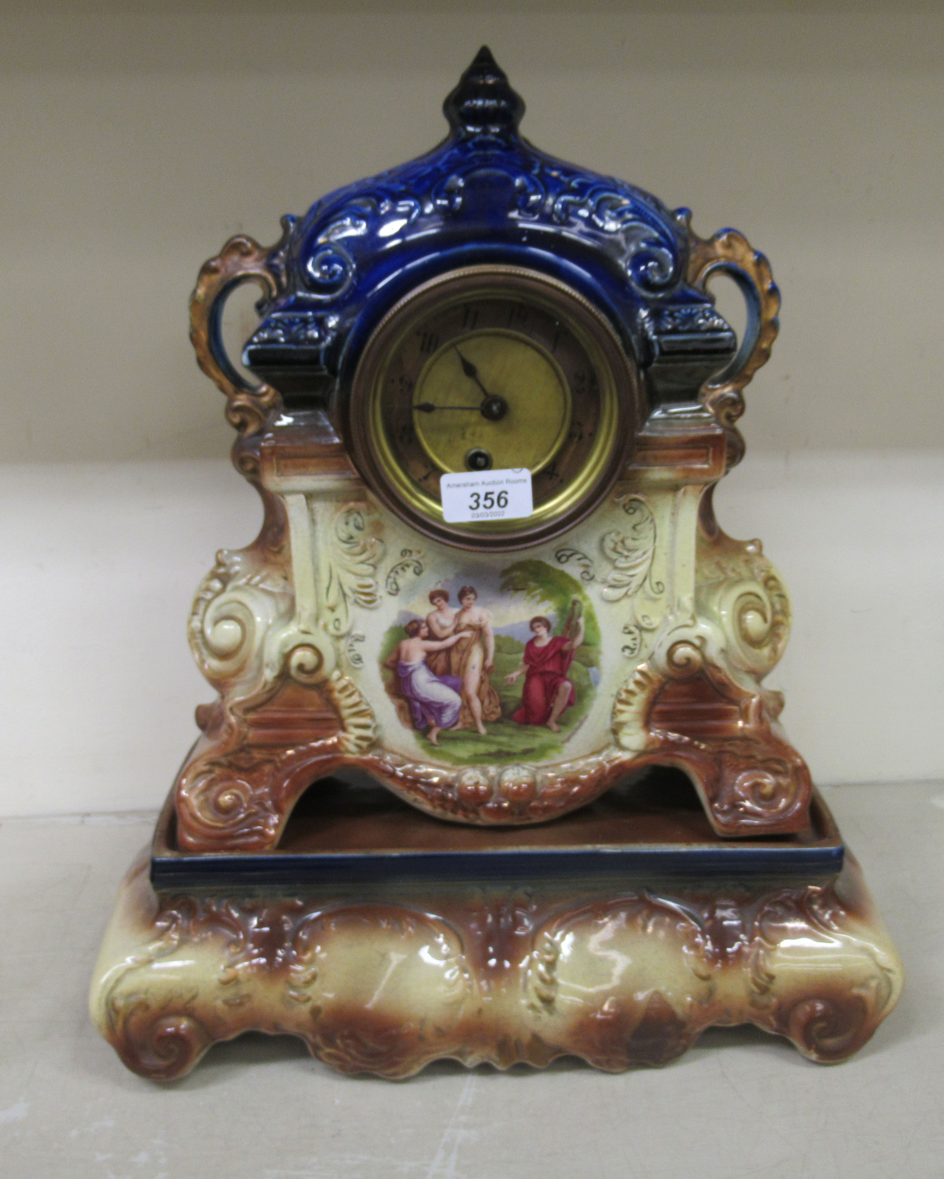 A late Victorian English china cased mantle clock; the movement faced by an Arabic dial, raised on