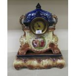 A late Victorian English china cased mantle clock; the movement faced by an Arabic dial, raised on