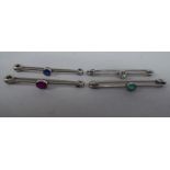 A set of four white metal wire pin brooches, each set with a single coloured stone