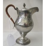 A Georgian style silver pedestal wine jug of ovoid form with a split cane clad, C-scrolled handle,