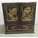 An early/mid 20thC Japanese black lacquered and gilded table top cabinet with a pair of doors,