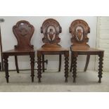 A pair of William IV oak hall chairs with carved, pierced backs, over a serpentine front seat and