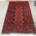 A Turkoman rug with a central panel bordered by stylised designs, on a mainly re ground  77" x 50"