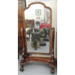 A Victorian flame mahogany framed cheval mirror, the shaped plate pivoting on scrolled horns, united