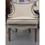 A modern studded white fabric upholstered salon chair with an inverted wing back and enclosed,